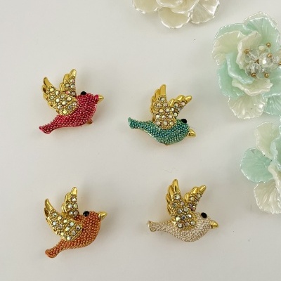 Broches de pássaros coloridos com pedras brilhantes sobre fundo branco e flores decorativas