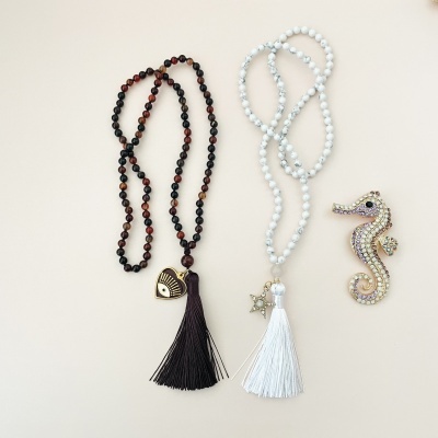 Colares de contas castanhas e brancas com franjas e broche de cavalo-marinho brilhante