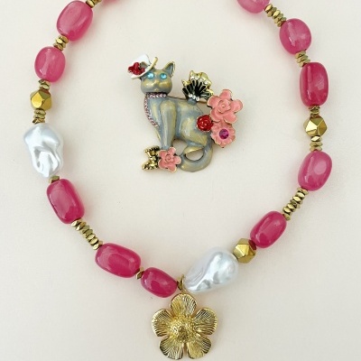 Colar rosa com pendente de flor dourada e broche decorativo de gato com flores