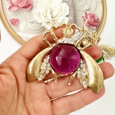 Bijuteria de abelha dourada com pedra púrpura e brilhantes