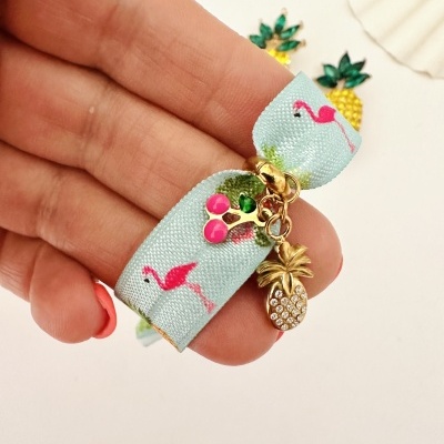Pulseira elástica azul clara com flamingos cor-de-rosa e pingentes dourados de cerejas e abacaxi com cristais