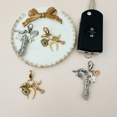 Dois porta-chaves decorativos dourado e prateado ao lado de uma chave de carro preta