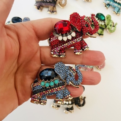 Broches em forma de elefantes com pedras coloridas brilhantes em fundo branco