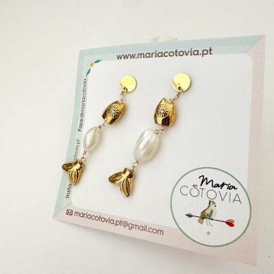brincos pendentes dourados e brancos em cartão de apresentação
