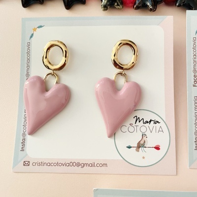 Brincos rosa em forma de coração com base dourada irregular em cartão de marca