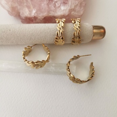 Dois pares de brincos de argola dourados com padrão de folhas, com uma pedra rosa ao fundo