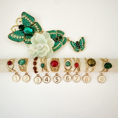 Nove anéis folheados a ouro com pedras coloridas e broche decorativo de borboletas e flor