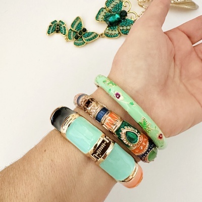 Pulseiras coloridas no pulso e colar com borboletas verdes e douradas