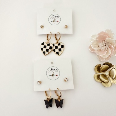 Conjuntos de brincos Maria Cotovia com corações xadrez e borboletas em fundo branco com flores decorativas