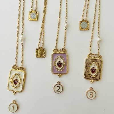 Colares dourados com pendentes retangulares coloridos com corações vermelhos e números pendurados.