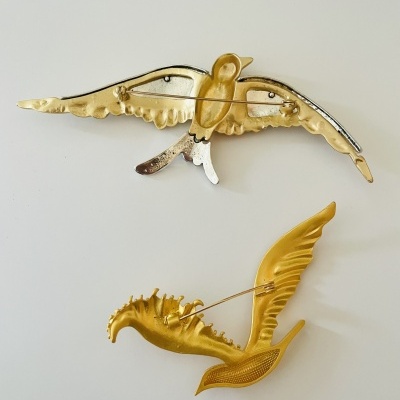 Presilhas metálicas douradas em forma de aves sobre fundo branco