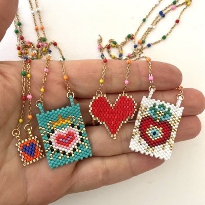 Quatro colares com pendentes de miçangas coloridas em formas de corações e morango