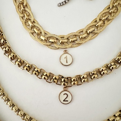 Pulseiras douradas de metal com pendentes numerados 1 e 2