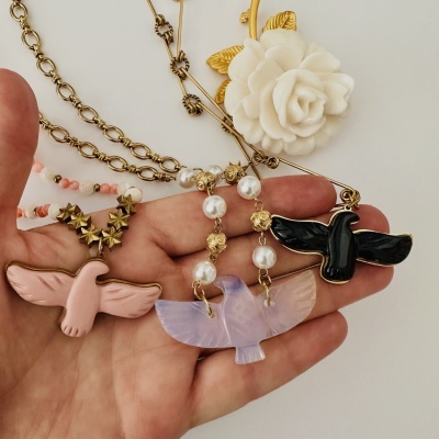 Colares com pendentes de pássaros coloridos e flores ao fundo