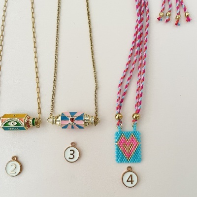 Três colares com pendentes coloridos diferentes etiquetados com números contra fundo branco