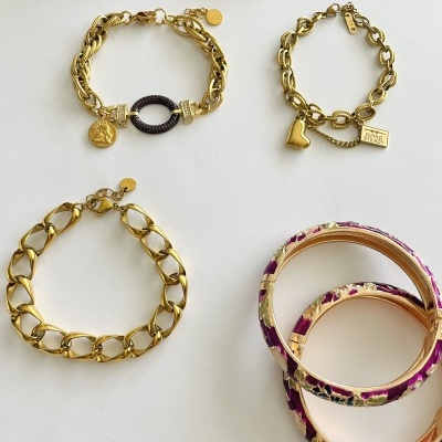 Conjunto de pulseiras douradas e bangles florais sobre fundo branco