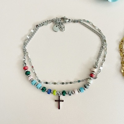 Colar prateado com contas coloridas e cruz sobre fundo branco