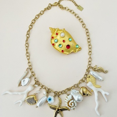 Colar dourado com pendentes marinhos e broche de concha com pedras coloridas