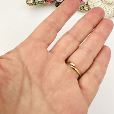 Mão com anel dourado simples e objeto decorativo colorido no fundo