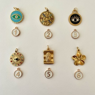 Seis pendentes dourados com diferentes desenhos e etiquetas numeradas