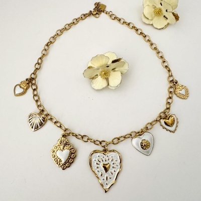 Colar dourado com pendentes de coração e acessórios florais brancos e dourados