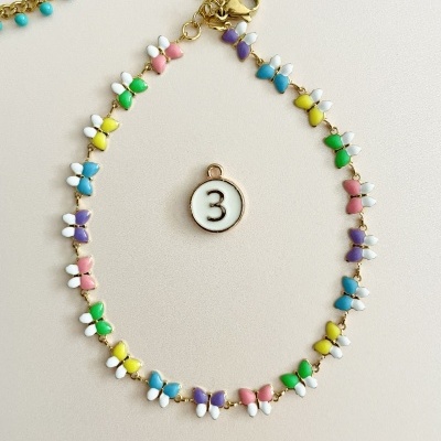 Colar com pendentes de borboletas coloridas e corrente dourada sobre fundo claro