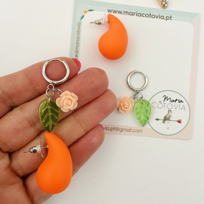 Par de brincos com detalhes em laranja, verde e cor de pêssego com cartão de marca e estrela-do-mar