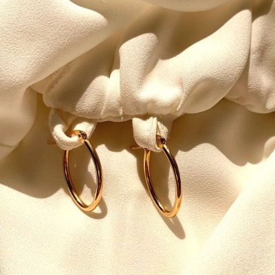 Brincos de argola dourados pendurados em tecido creme