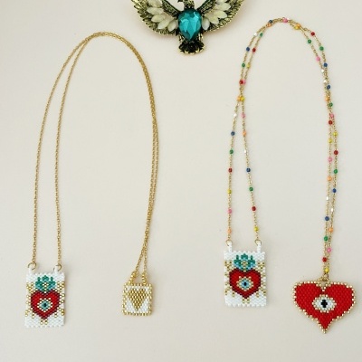Colares com pingentes de contas em forma de coração e flor, e alfinete de pássaro azul e branco.