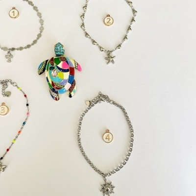 Pulseiras prateadas e broche colorido em fundo branco com etiquetas numeradas