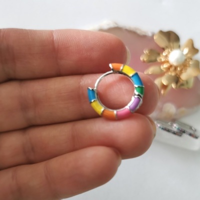 Anel pequeno colorido em esmalte segurado entre os dedos