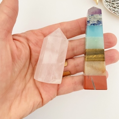 Mão segurando duas pedras lapidadas coloridas tipo obelisco