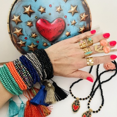 Pulseiras coloridas, anéis dourados com pedras, colares com pendentes de coração, prato decorativo com coração e estrelas.