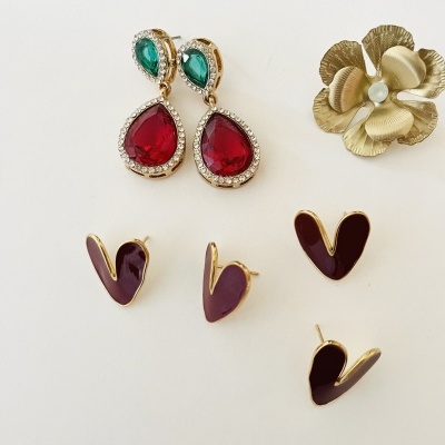 Três pares de brincos e um broche flor dourado com pérola sobre fundo branco