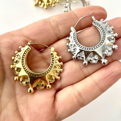 Brincos argola dourado e prateado com detalhes em relevo em mão