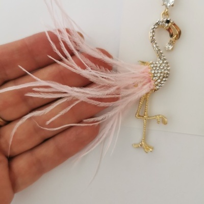 Brinco de flamingo dourado com pedras brilhantes e penas cor-de-rosa em fundo branco