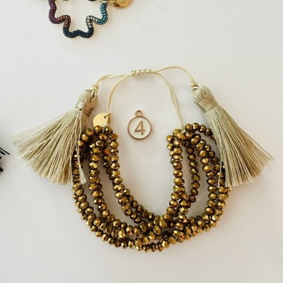 Pulseira com contas douradas brilhantes e pompons bege com etiqueta número 4