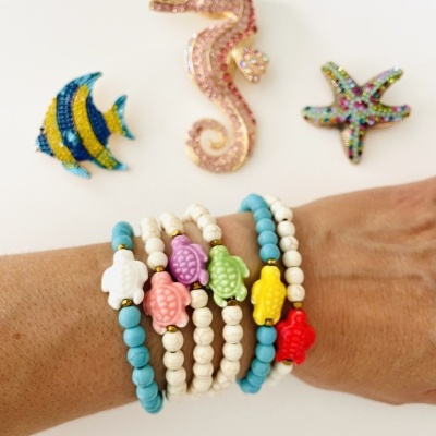 Pulseiras coloridas com pingentes de tartaruga e broches marinhos brilhantes em fundo branco