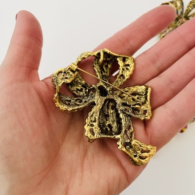 Broche dourado texturizado segurado numa mão