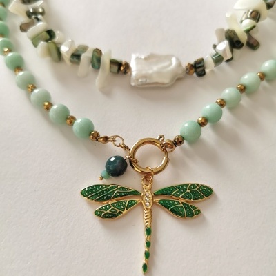 Colares com pedras esbranquiçadas e pérola, outro com contas verdes e pendente de libélula dourada com detalhes verdes.