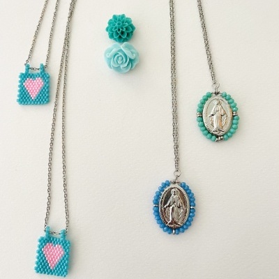 Colares com pingentes de contas azuis e medalhas religiosas, e brincos florais azuis claros