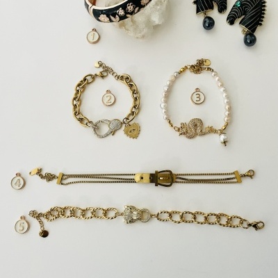 Acessórios de bijuteria variados sobre fundo claro, incluindo pulseiras e brincos com detalhes em dourado, preto, pérolas e verdes.