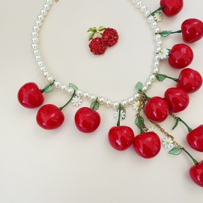 Colar de pérolas com pendentes de cerejas vermelhas e broche de cerejas ao centro