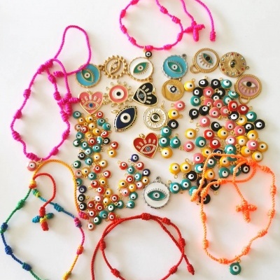 Acessórios de bijuteria coloridos com cordões e medalhões decorativos sobre fundo branco.