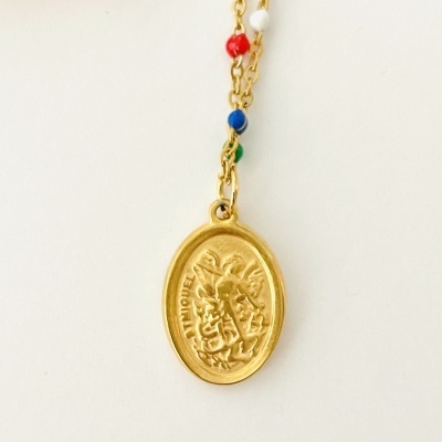 Colar dourado com medalha oval e contas coloridas em fundo branco