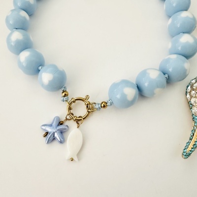 Colar com contas azuis de bolinhas brancas e pendentes de estrela do mar e peixe, fecho dourado.