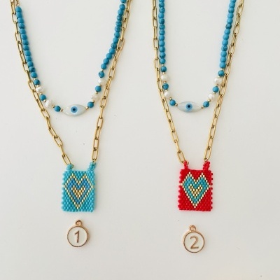 Dois colares com pendentes de miçangas azul e vermelho com padrão em forma de coração.
