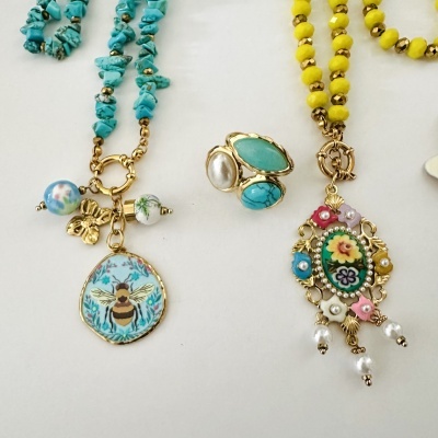 Conjunto de colares e anel com pedras e pendentes floridos sobre fundo branco