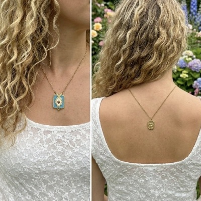 Colar dourado com pendente azul e floral em mulher com vestido branco de renda