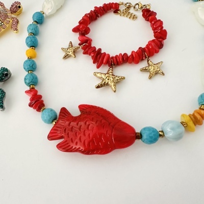 Pulseira vermelha com estrelas do mar douradas